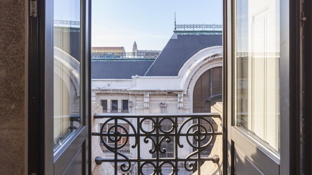 A balcony with wrought iron railings overlooking a historic building with a clock tower. - BO - Bolhão Apartments (Porto)
