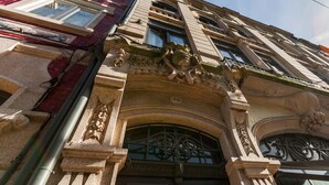 A building facade with ornate architectural details, including a large arched entrance and decorative stonework. - BO - Bolhão Apartments (Porto)