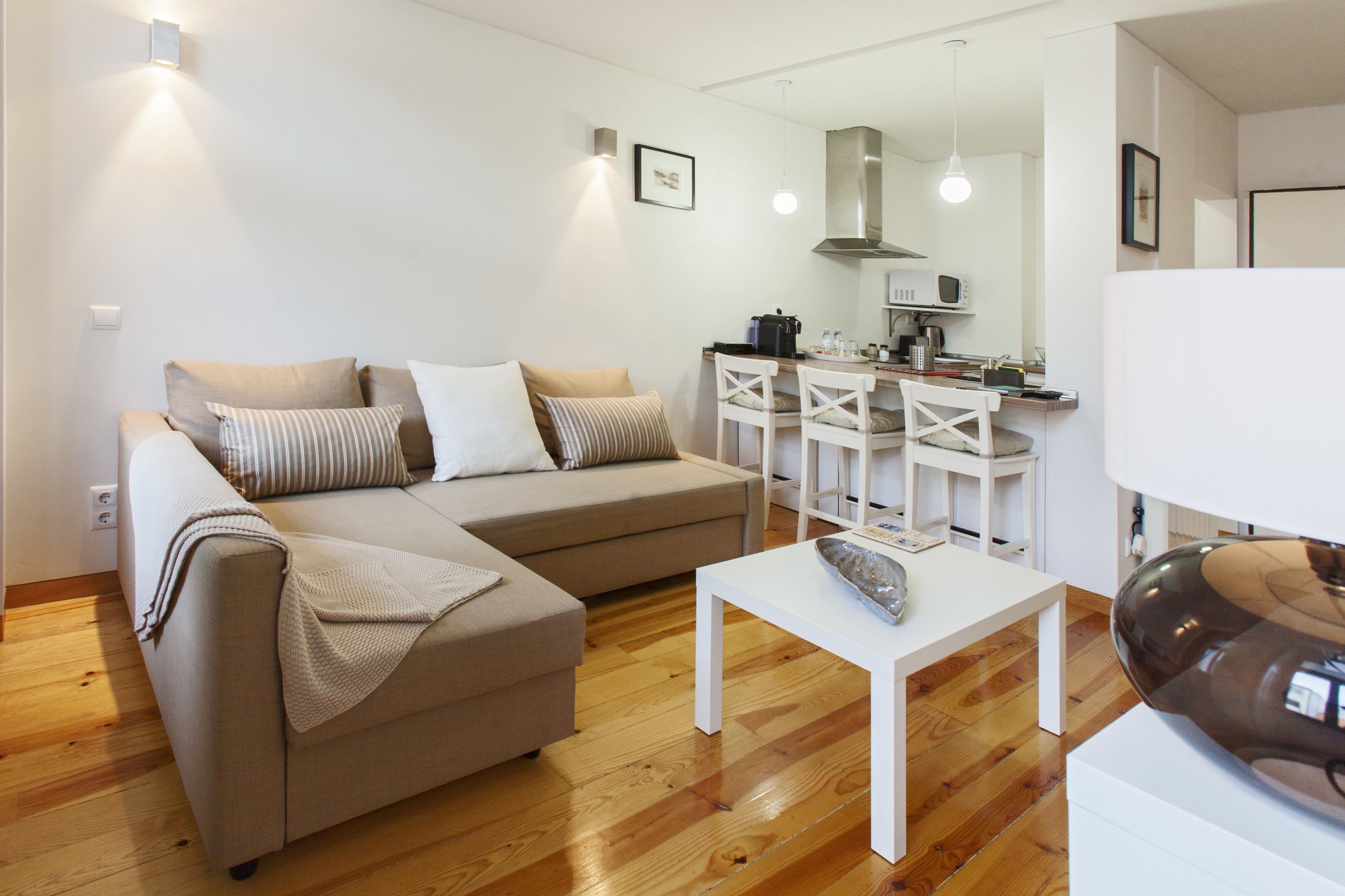 A modern living room with a sofa, a coffee table, and a kitchen area in the background.