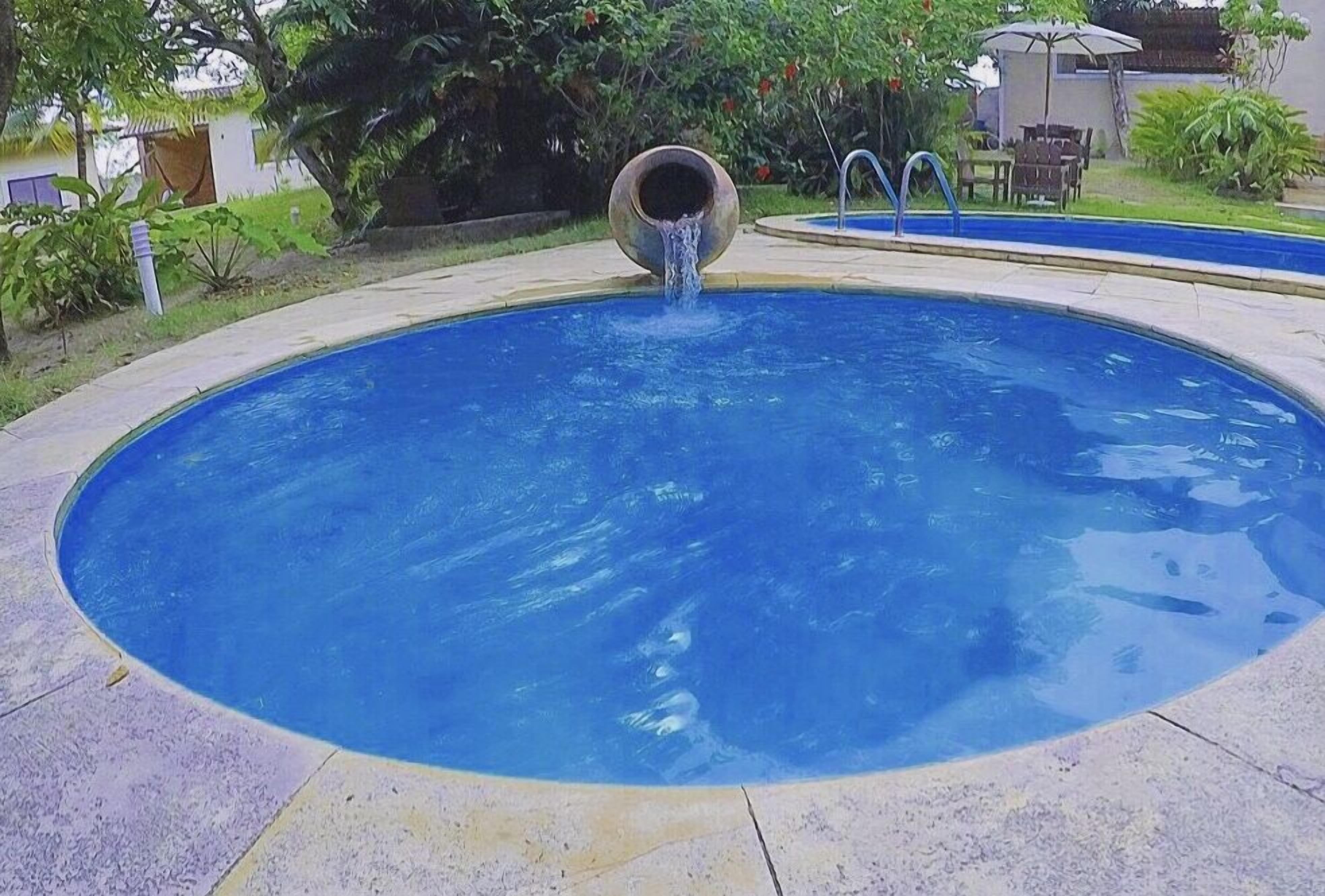 A circular pool with a water spout in the center, surrounded by a tiled deck.