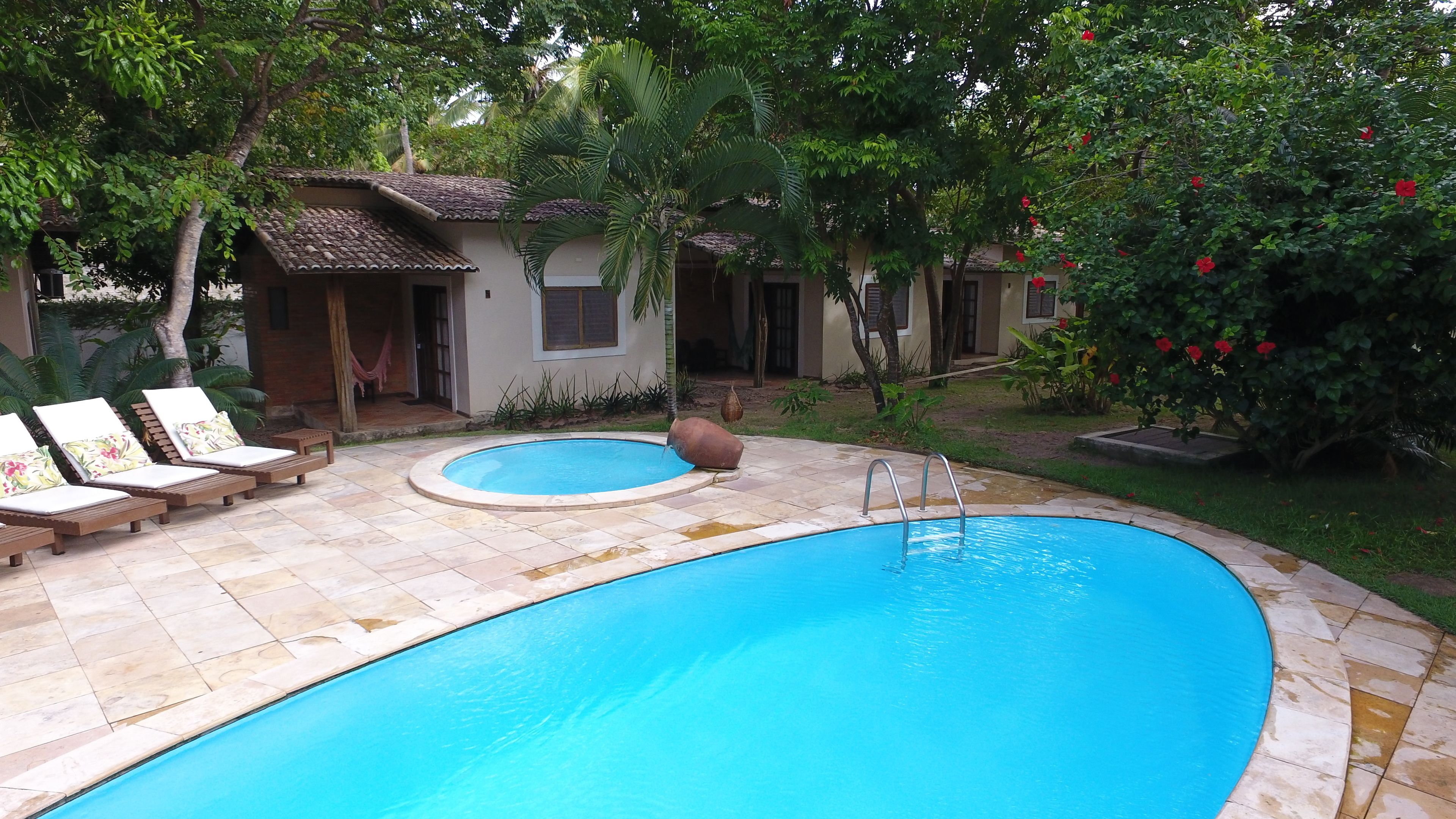 Una piscina con lettini e una piccola casa sullo sfondo.