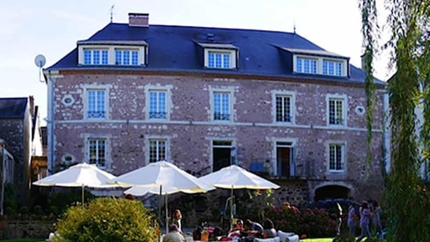 A large brick building with multiple windows and a garden area with outdoor seating. - Auberge de l'Abbaye (Thiron-Gardais)