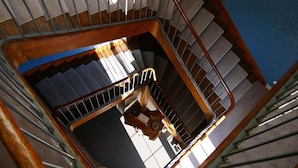 A spiral staircase with a wooden handrail and metal balusters, leading to a landing with a control panel and a view of the sky. - Auberge de l'Abbaye (Thiron-Gardais)