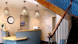 A reception desk with a clock, a counter, and a small display. - Auberge de l'Abbaye (Thiron-Gardais)