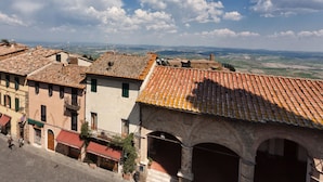 Une ville historique aux bâtiments aux toits de tuiles en terre cuite, aux arches de pierre et à la rue pavée.