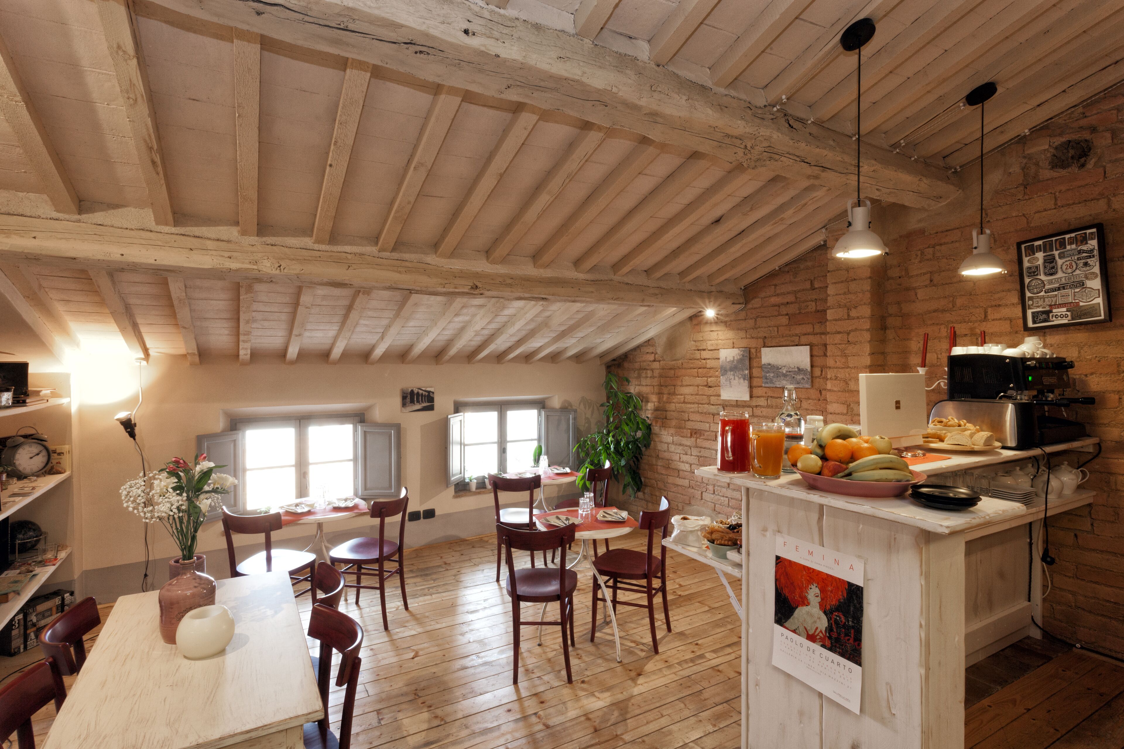 A rustic kitchen with wooden beams, a dining area with wooden chairs, and a bar counter with fruit and a coffee machine.