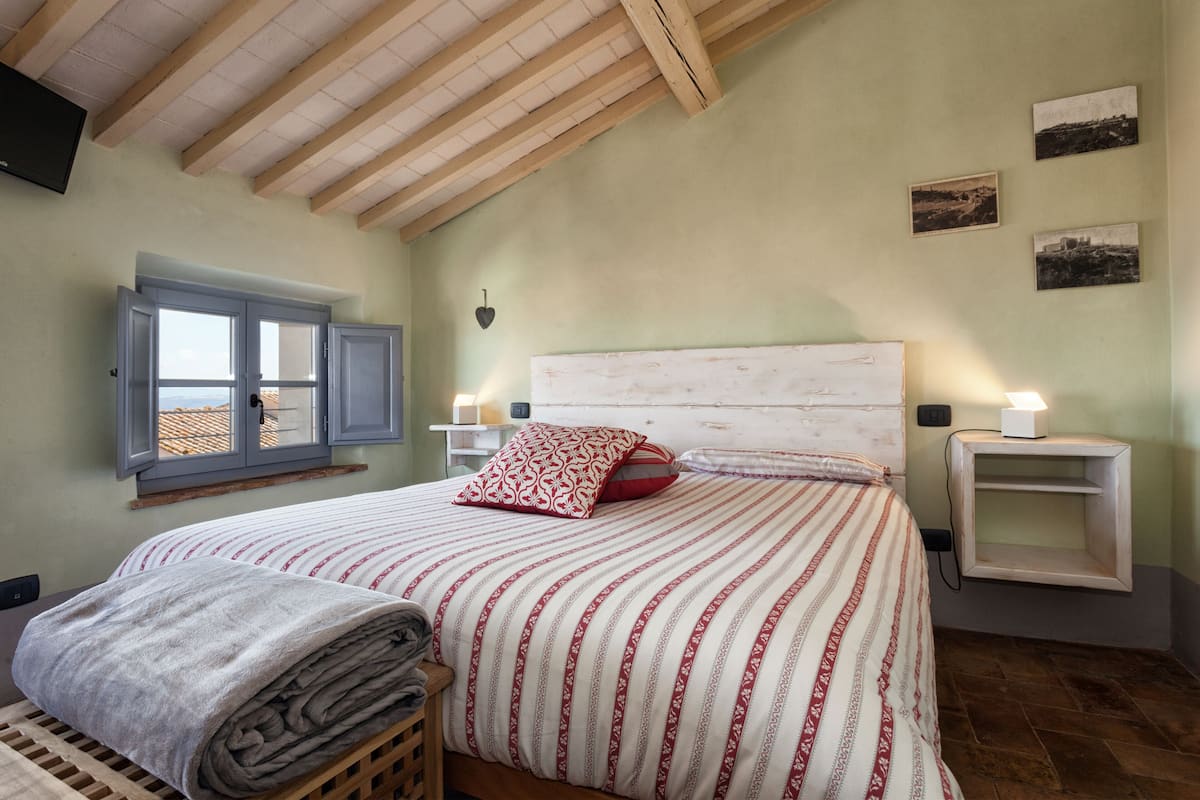 Une chambre à coucher comprenant un lit, une fenêtre, une table de chevet et une étagère fixée au mur.