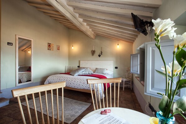 A bedroom with a bed, a chair, a desk, a mirror, and a television. - B&B Le Scalette di Piazza (Montalcino)