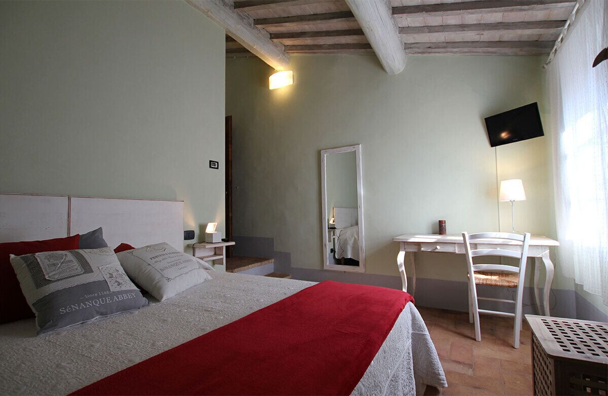 Une chambre à coucher avec un lit, un bureau, une chaise, un miroir et une télévision.