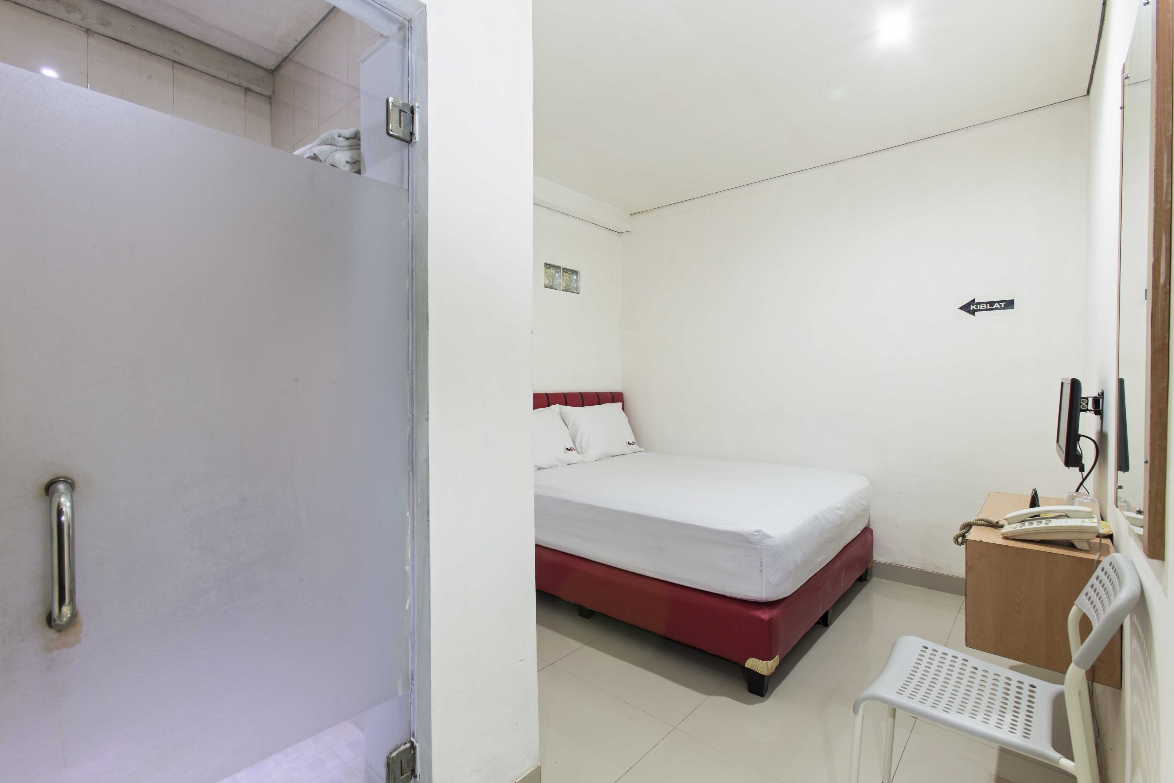 A hotel room with a bed, a desk with a telephone, and a chair.