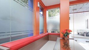 Un intérieur moderne avec un banc rouge, une plante en pot et une cloison en verre.