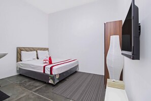 A hotel room with a bed, a television, and a large decorative vase.