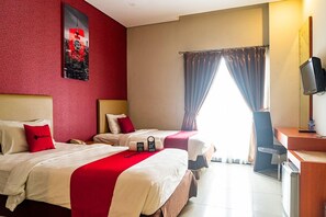 A hotel room with two beds, a desk, a television, and a window with curtains. - RedDoorz Blok M (Jakarta)