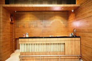 A reception desk with a wooden finish, a clock on the wall, and a trophy on the counter.
