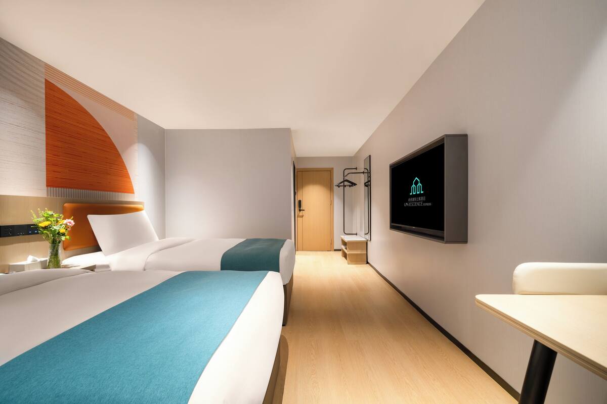 Una habitación de hotel moderna con cama, televisión, escritorio y zona de ducha.