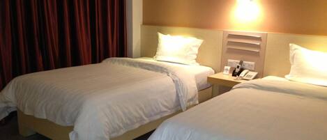 A hotel room with two beds, a nightstand with a phone and a lamp, and a curtain.