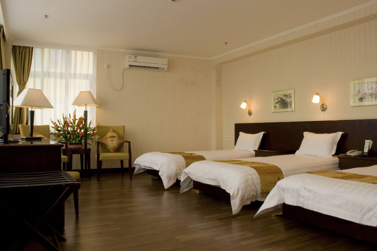 Una habitación de hotel con dos camas, un escritorio, una silla y un televisor.