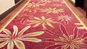 A long, narrow hallway with a red carpet featuring large floral patterns. - Guang Dong Hotel (Guangzhou)