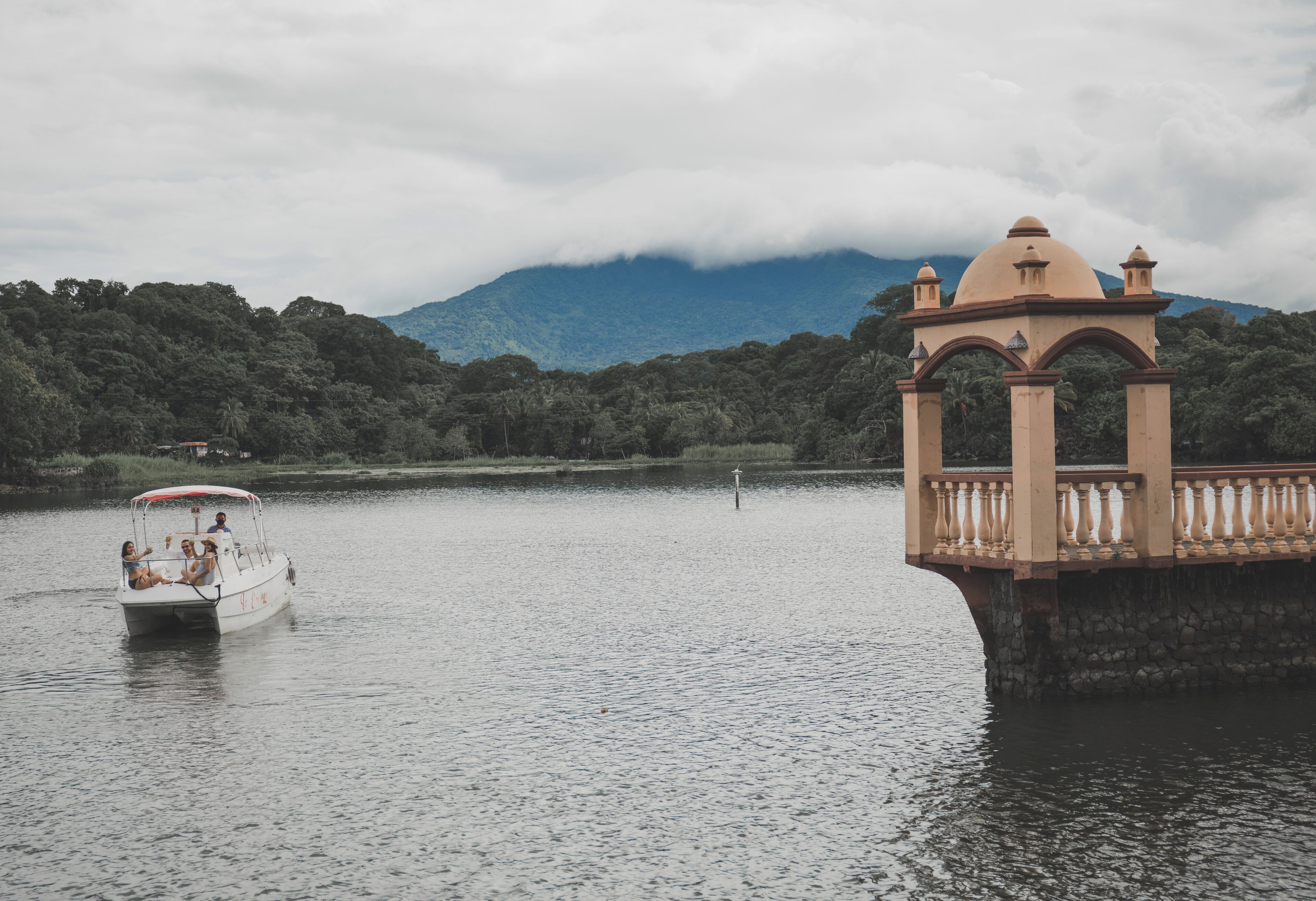 Un bateau sur un lac paisible, avec un kiosque sur la rive.
