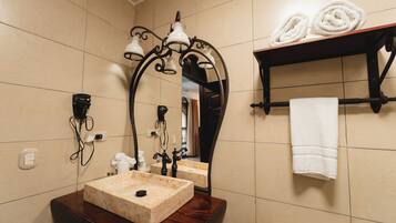 Un baño con lavamanos de mármol, un espejo con marco decorativo, un perchero con toallas y un calentador de pared.