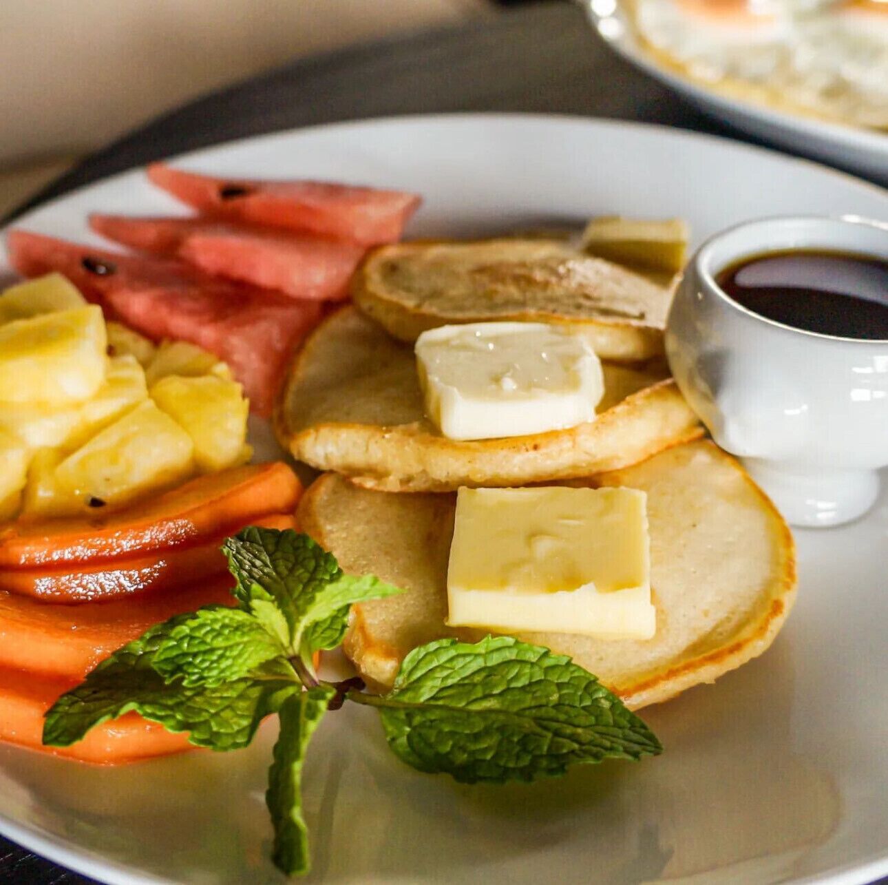 Un plato con tostadas, mantequilla, piña y zanahorias.