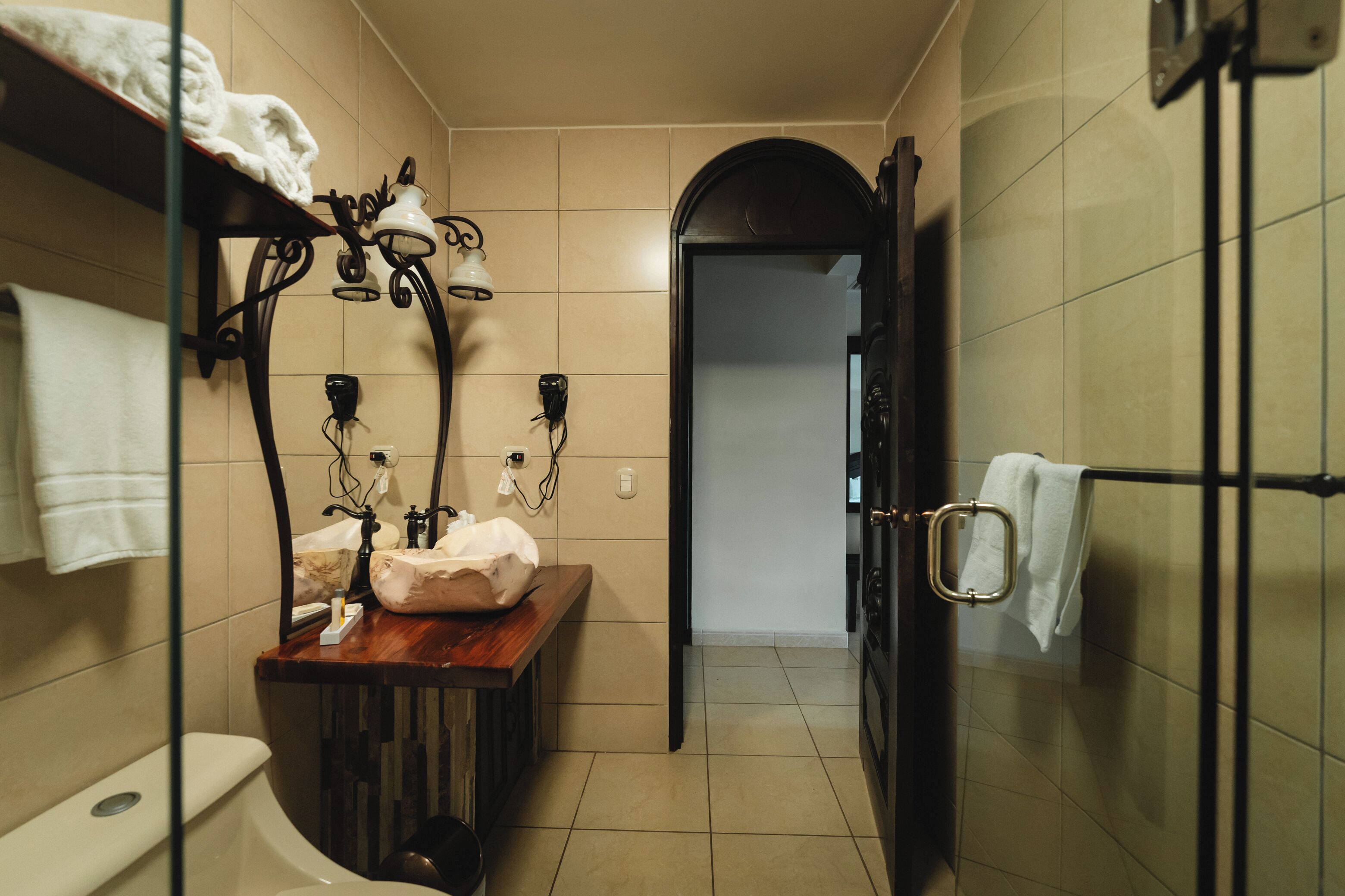 A narrow bathroom with a toilet, sink, and shower area.