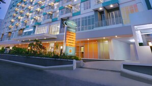 Een hoog hotel met meerdere verdiepingen, balkons en een goed verlichte gevel.