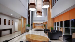 Een moderne lobby met een receptiebalie, een zithoek en grote ramen.