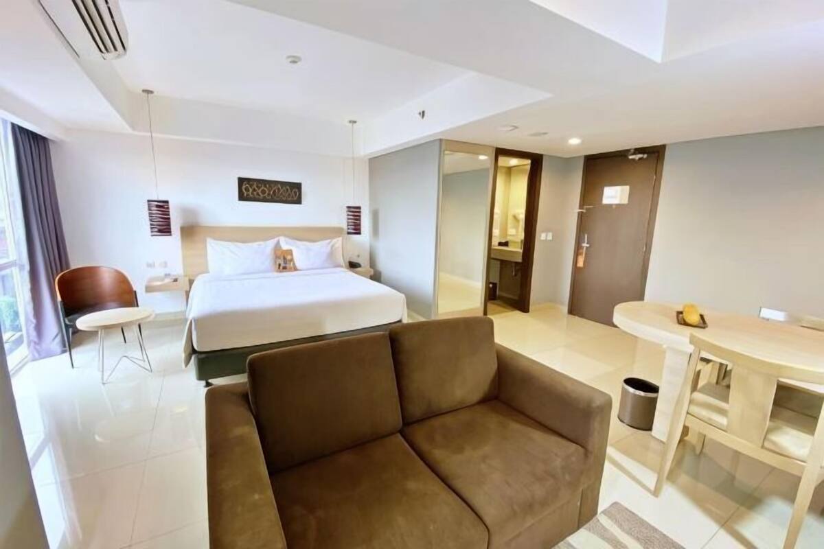 Ein Hotelzimmer mit einem Bett, einer Couch, einem Schreibtisch und einem Badezimmer.