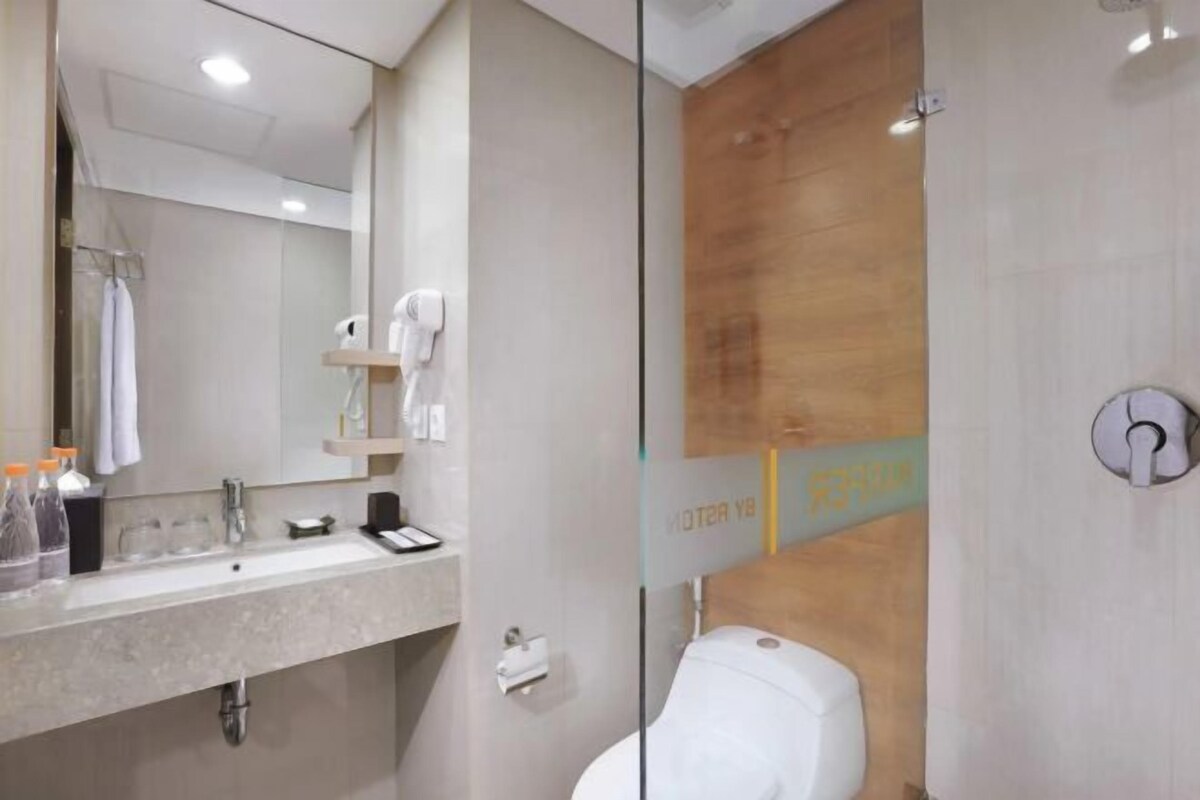 Un baño moderno con cabina de ducha de vidrio, lavabo con artículos de aseo y retrete.