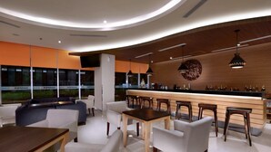 Een moderne bar met een gebogen plafond, houten details en een toog met krukken.