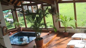 En træterrasse med jacuzzi, plantekasser og hvide stole.