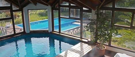 Una piscina techada, una piscina al aire libre de temporada, sombrillas