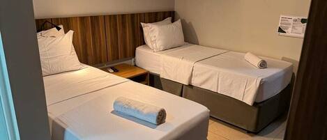 A room with two beds, a wooden headboard, a small table, and a wall-mounted sign.