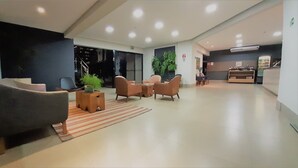 A modern lobby with a reception desk, seating area, and a staircase leading to an upper floor. - Hotel Horto (Rondonopolis)