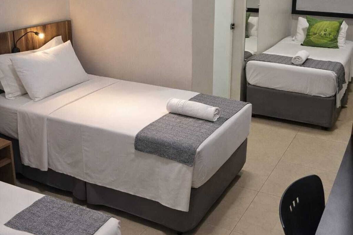 Une chambre d’hôtel avec deux lits, un bureau et une chaise.