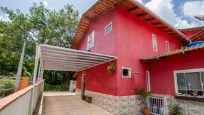 A red building with a covered patio, a small garden, and a brick pathway.