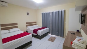 A hotel room with two beds, a desk, a television, and a window with curtains.