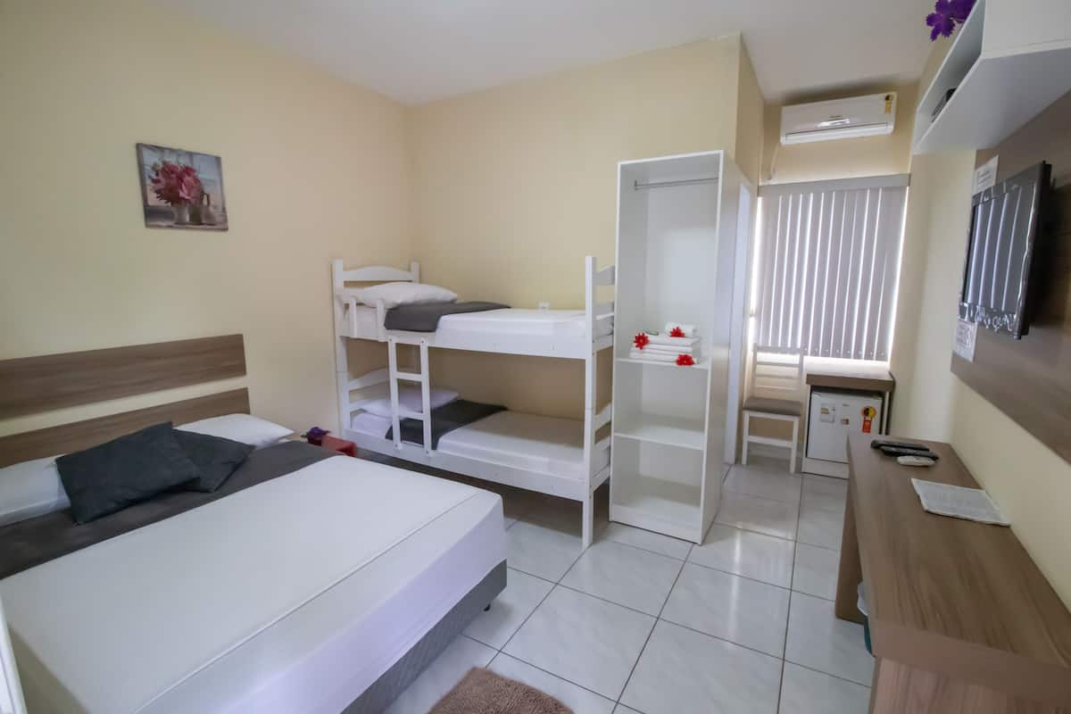 A bedroom with bunk beds, a desk, a chair, and a small kitchenette.