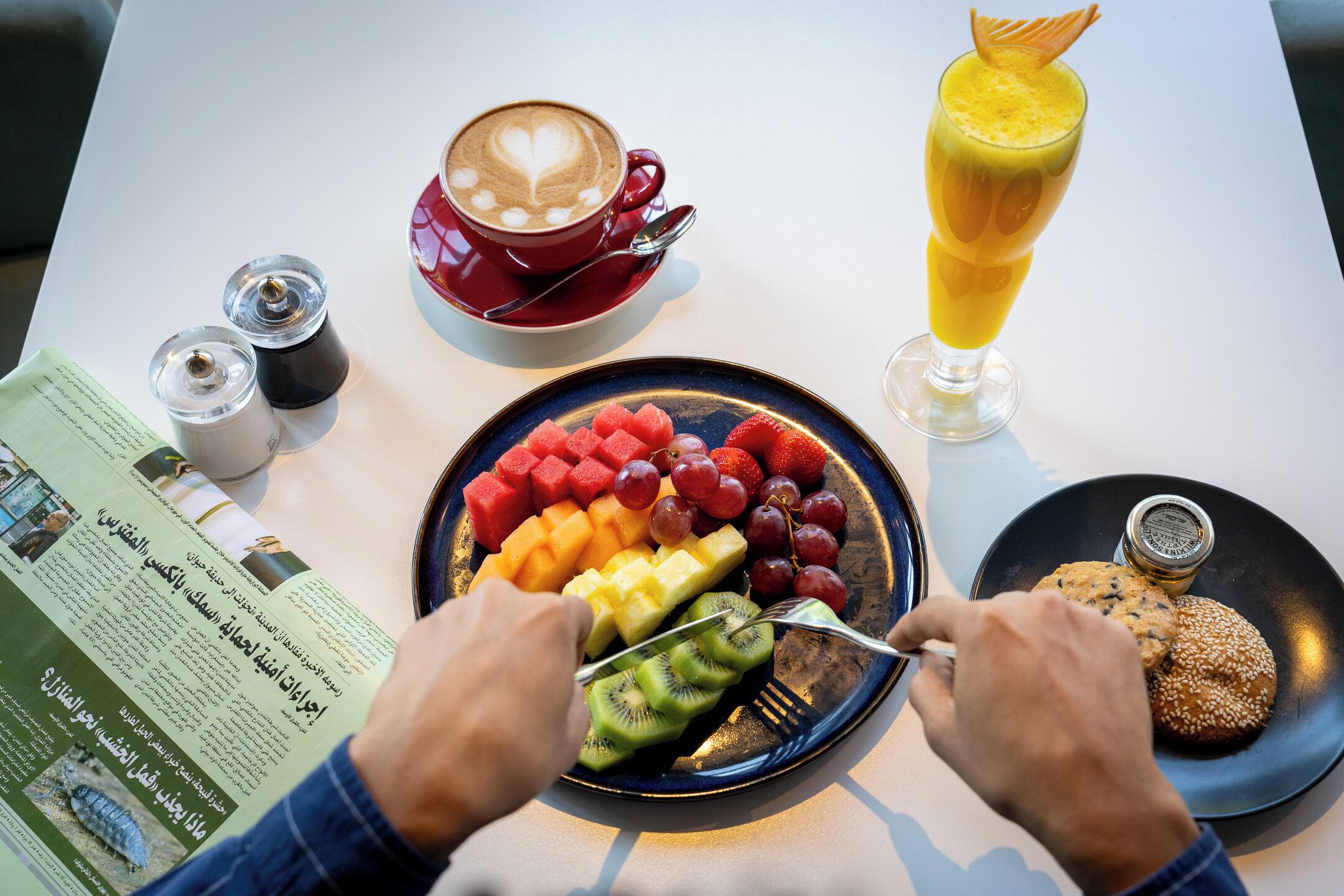 Ein Frühstückstisch mit einer Fruchtschale, einer Kaffeetasse und einem Glas Saft.
