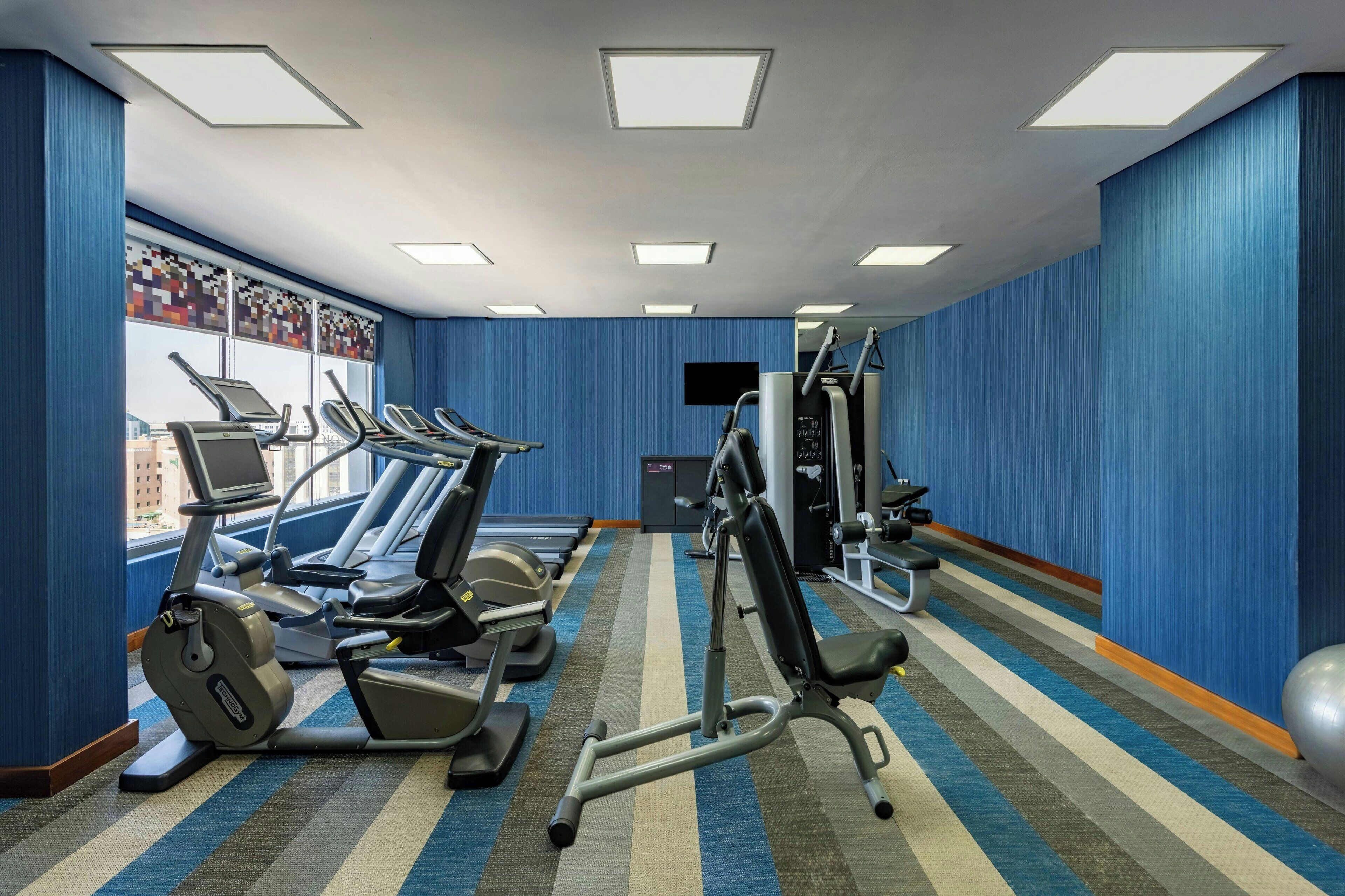 Une salle de sport équipée de tapis de course, de vélos elliptiques et de matériel de musculation.