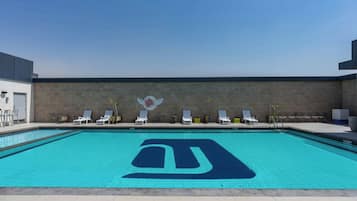 Una piscina al aire libre, sillones reclinables de piscina
