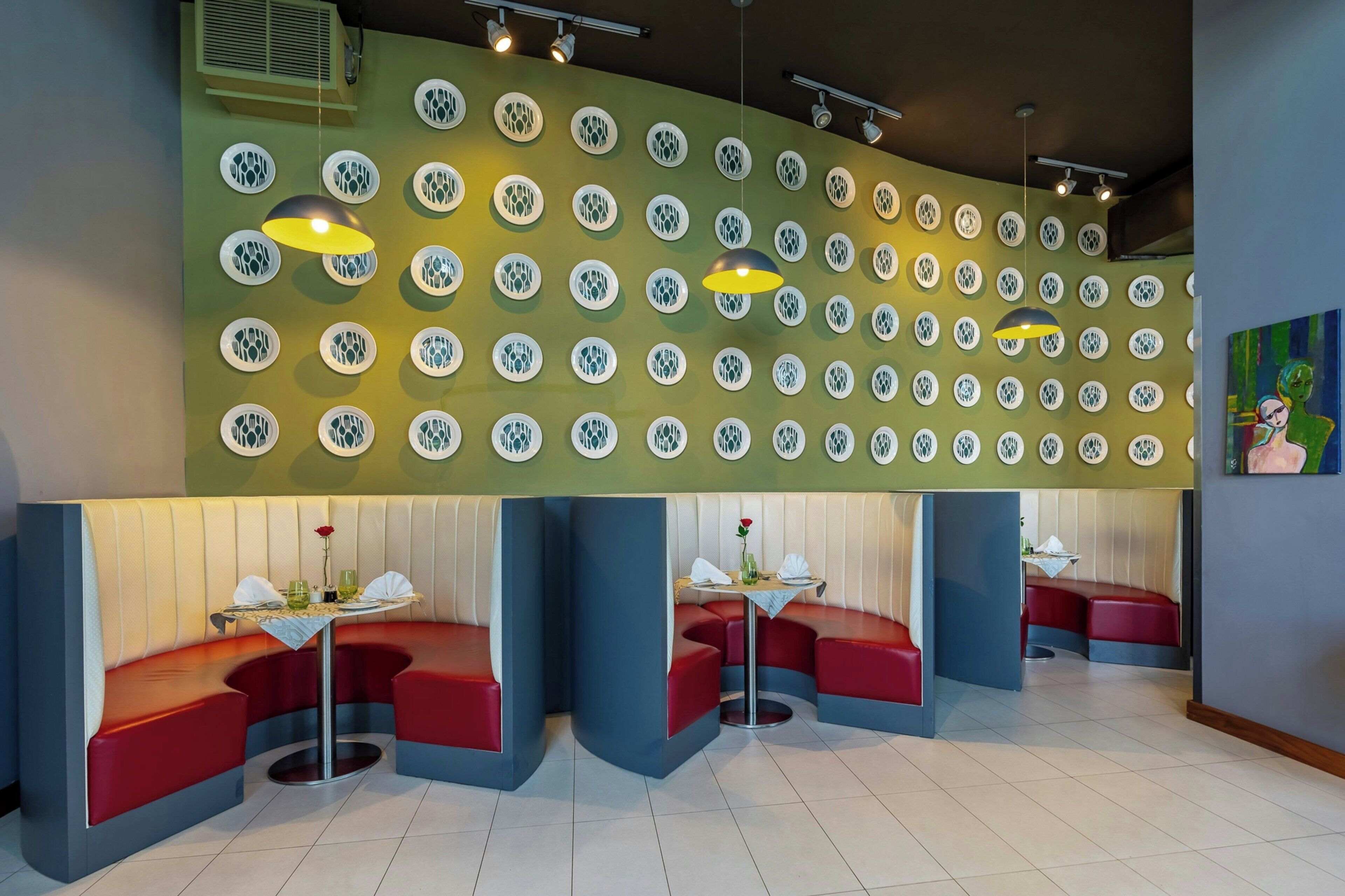 Un restaurant amb seients en cabines, un mur amb dibuixos i il·luminació penjant.