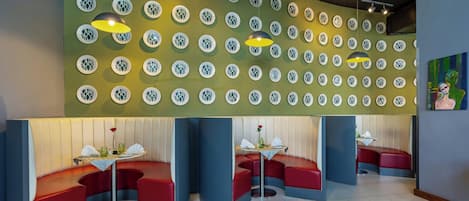 A restaurant with booth seating, a patterned wall, and pendant lighting.