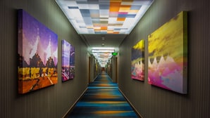A hallway with colorful artwork on the walls and a multicolored carpet. - Aloft by Marriott Riyadh (Riyadh)