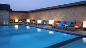 A swimming pool with lounge chairs and a stone wall.