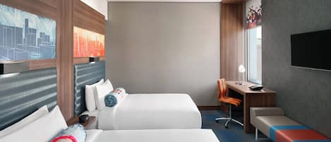 Habitación de hotel con dos camas, un escritorio, una silla, un banco, televisión y obras de arte en las paredes.