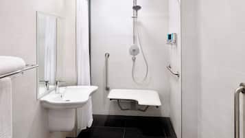Uma casa de banho moderna com lavatório branco, espelho e zona de duche.