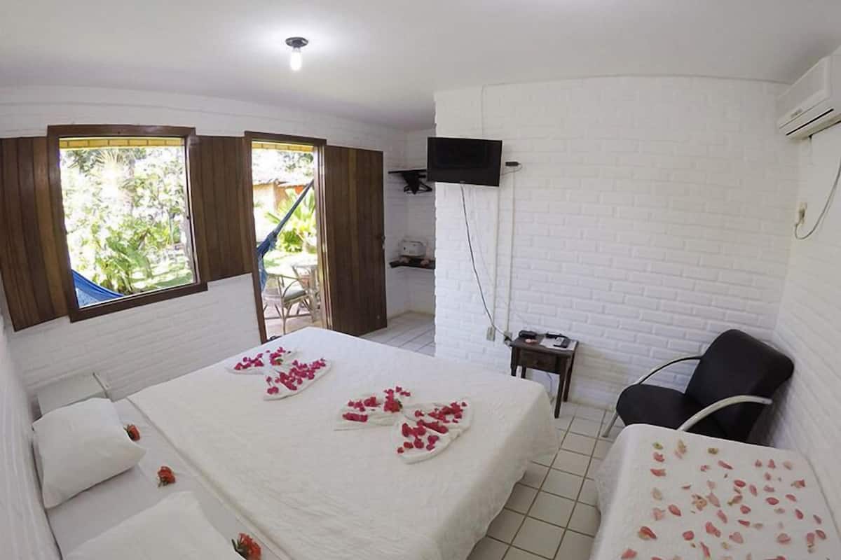 Una habitación de hotel con una cama, televisión, una silla y una mesita.