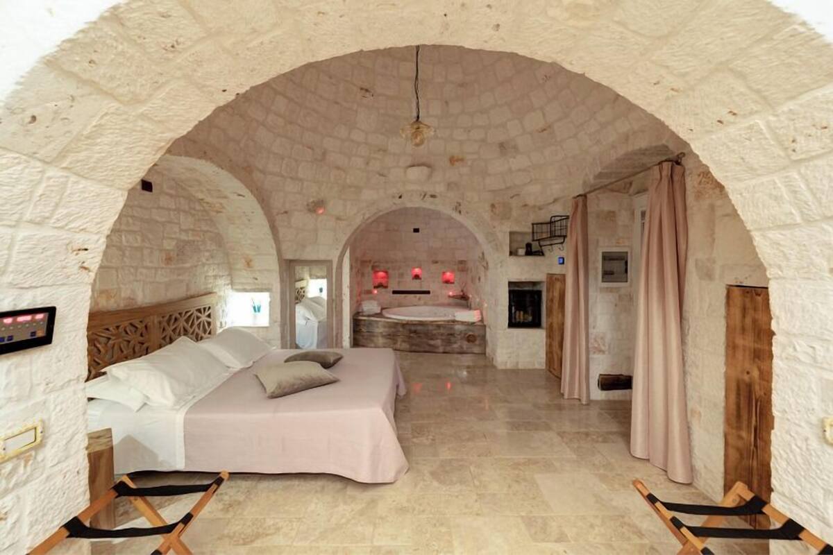 Ein Schlafzimmer mit einem Steingewölbe, einem Bett, einer Badewanne und einem Kamin.